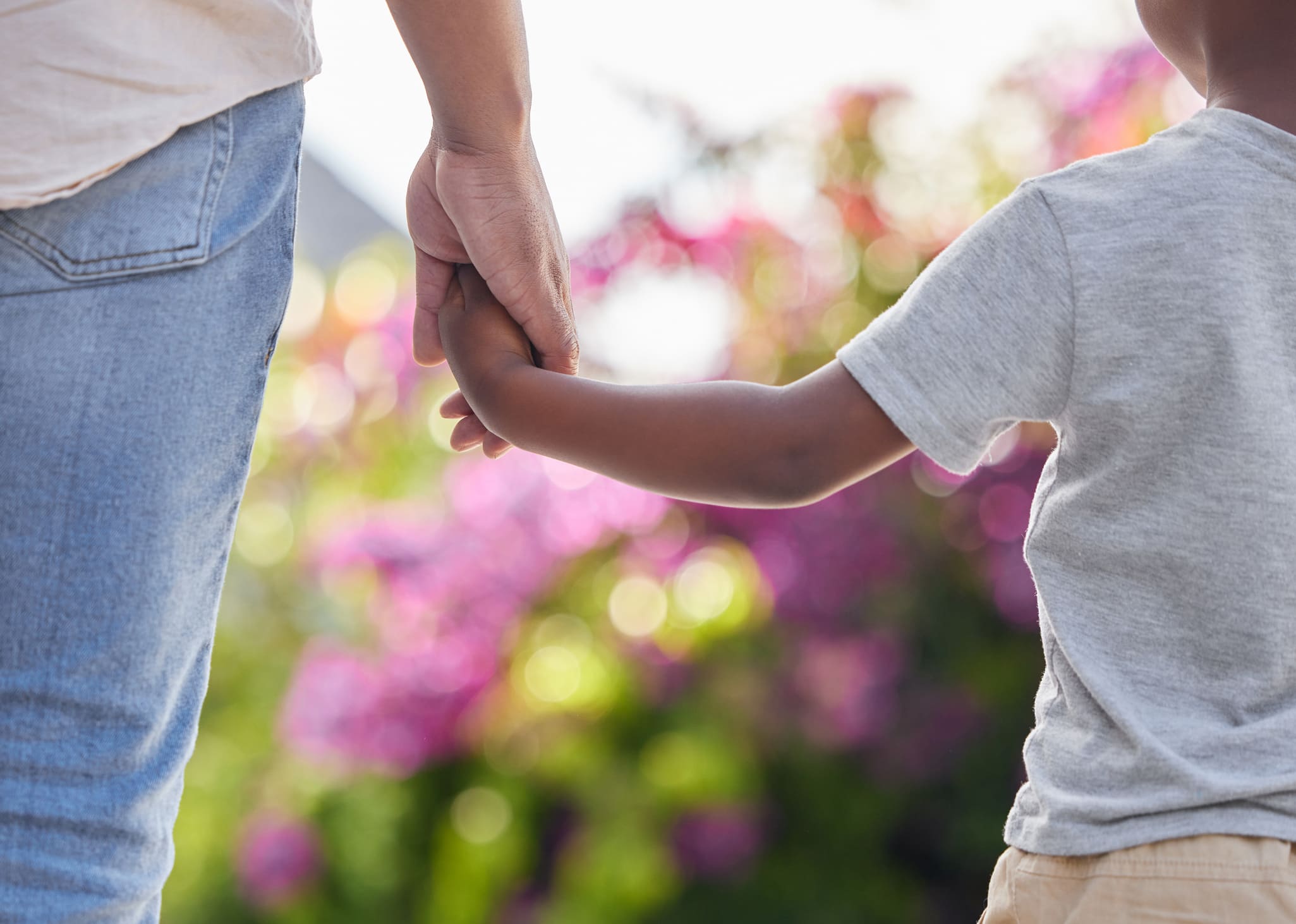Parent and child holding hands outdoors to highlight putting children first when agreeing custody and contact after divorce