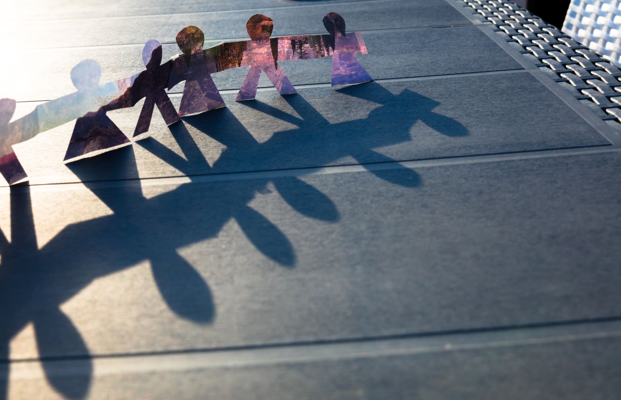 Paper chain of people casting long shadows to represent couples working together to reach an amicable divorce agreement